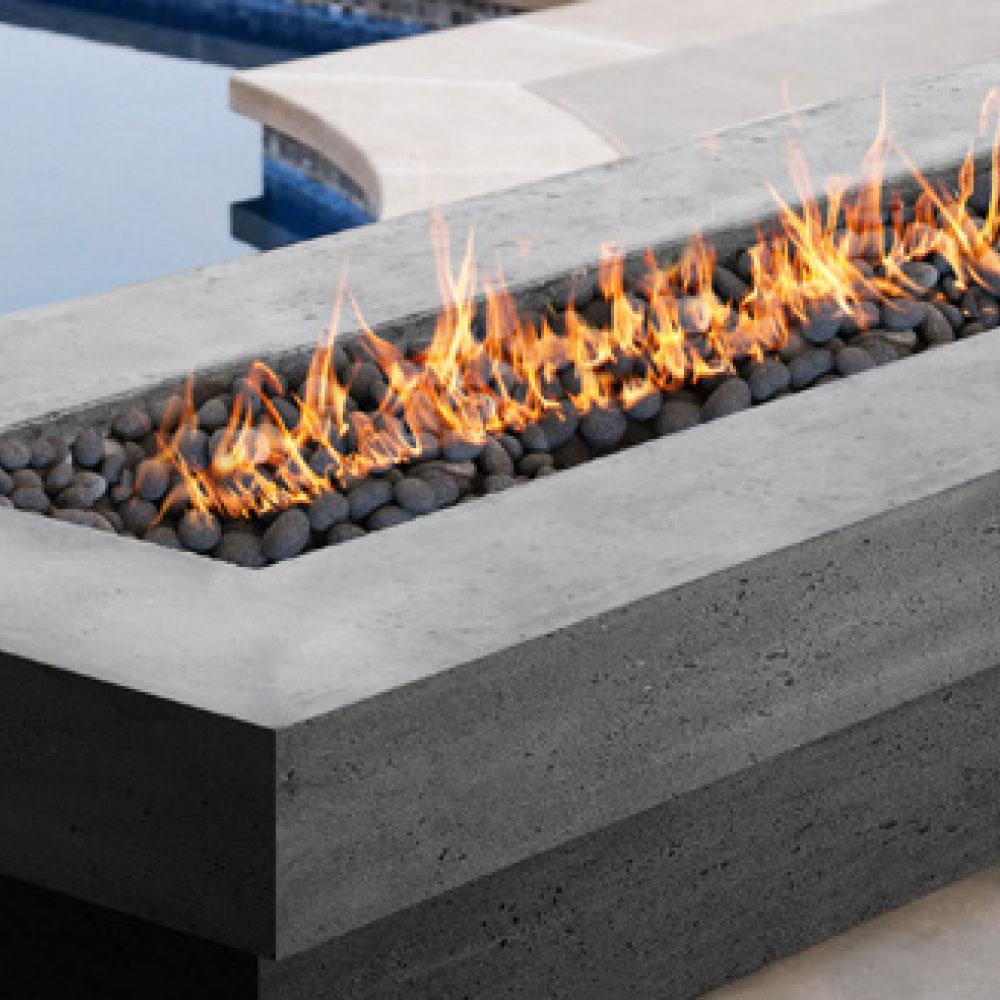 Concrete gas fire pit with glowing flames over lava rock burner bed