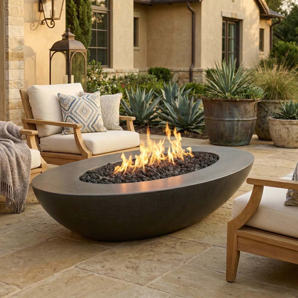 Dark gray oval concrete gas fire pit with burning flames and lava rocks