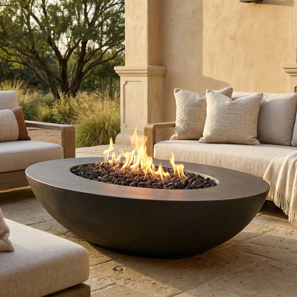 Light grey oval concrete gas fire pit with flames above black lava rocks