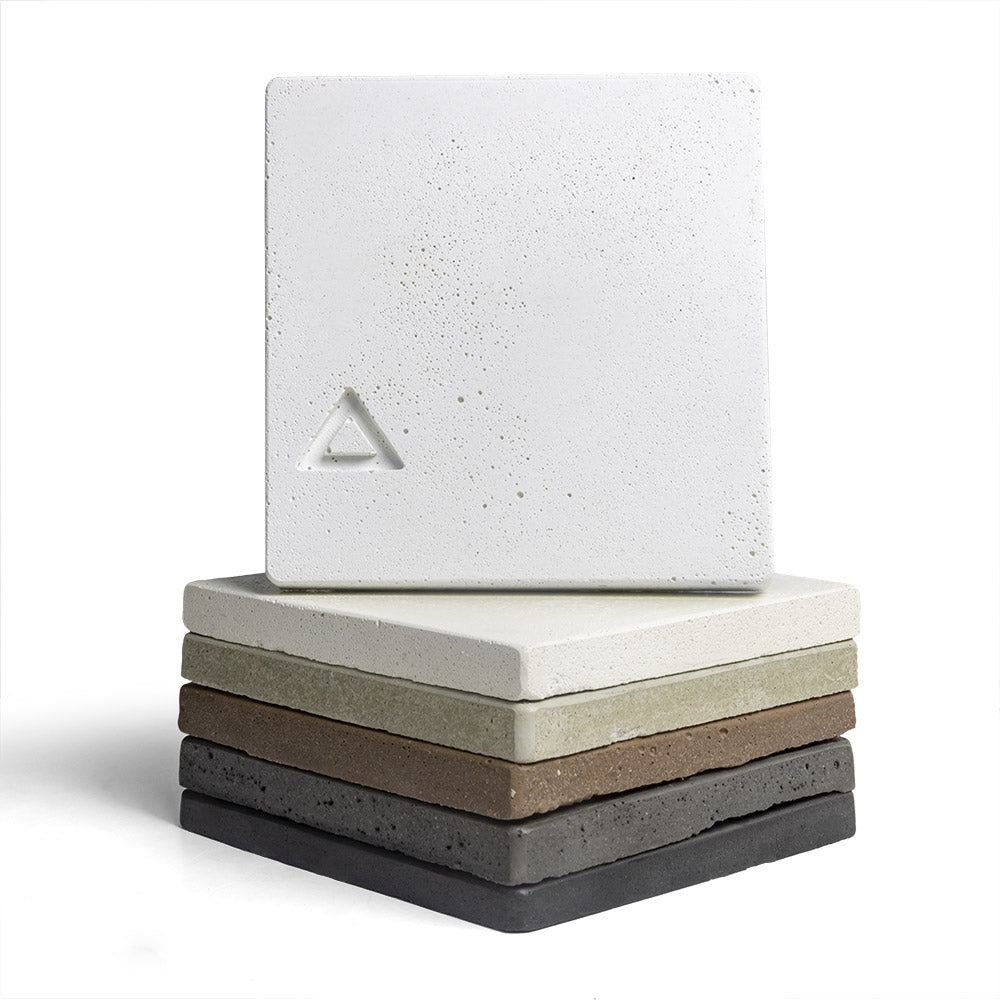 Concrete chip sample stack, light white-gray speckled squares with small triangular logo.