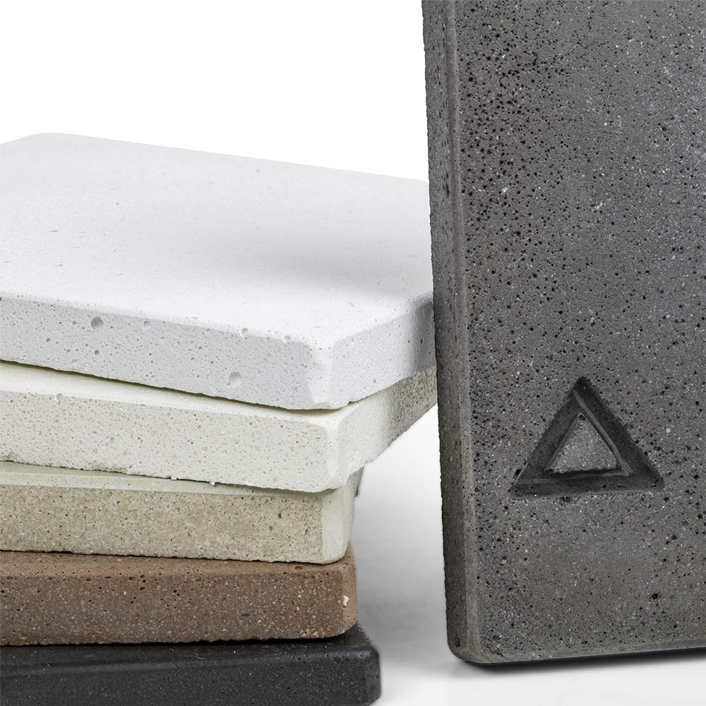 Concrete chip sample close-up: white and cream blocks, brown and dark gray layers, triangle mark.