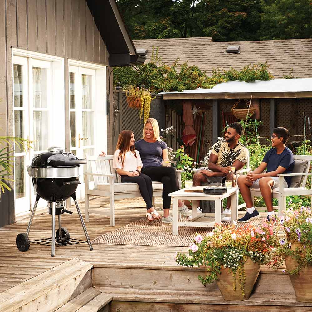 Charcoal kettle grill with black lid and silver body on a patio