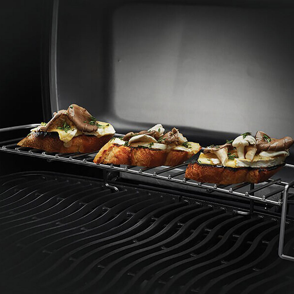 Portable propane grill with roasted chicken and vegetables on ridged cooking grate