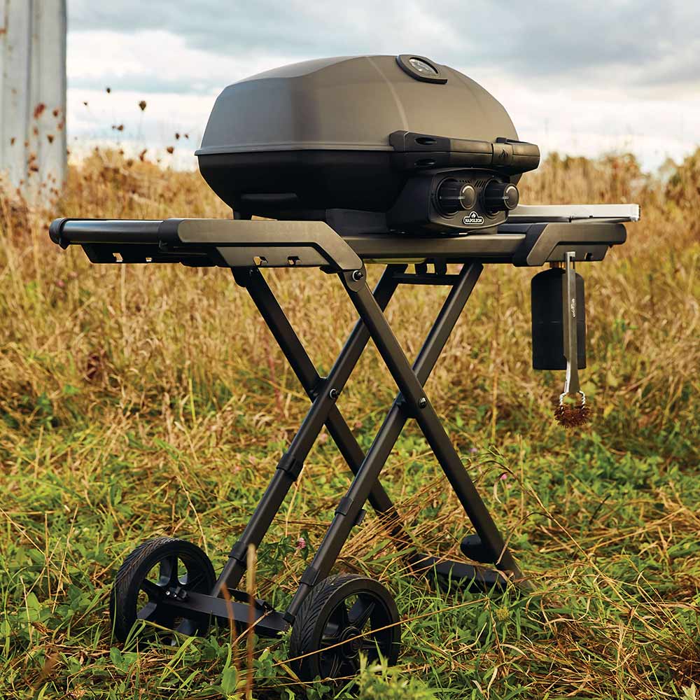 Black portable propane grill on scissor cart with side shelf and two wheels