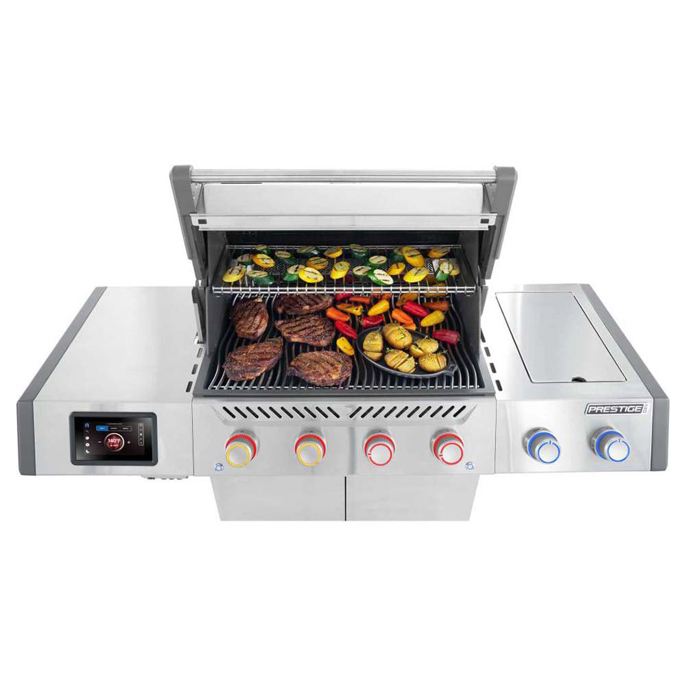 Stainless steel gas grill lid open with food cooking on grates and side trays