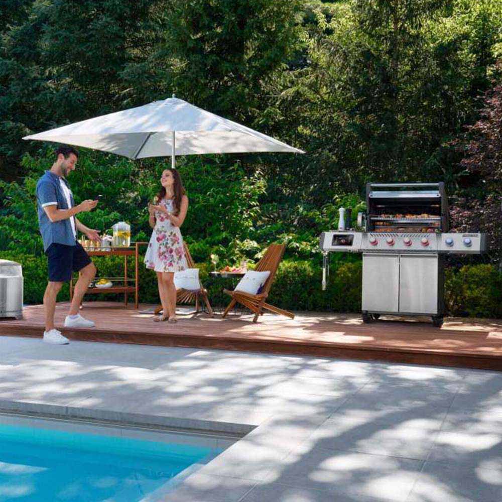 Stainless steel gas grill on a patio with side shelves and control panel