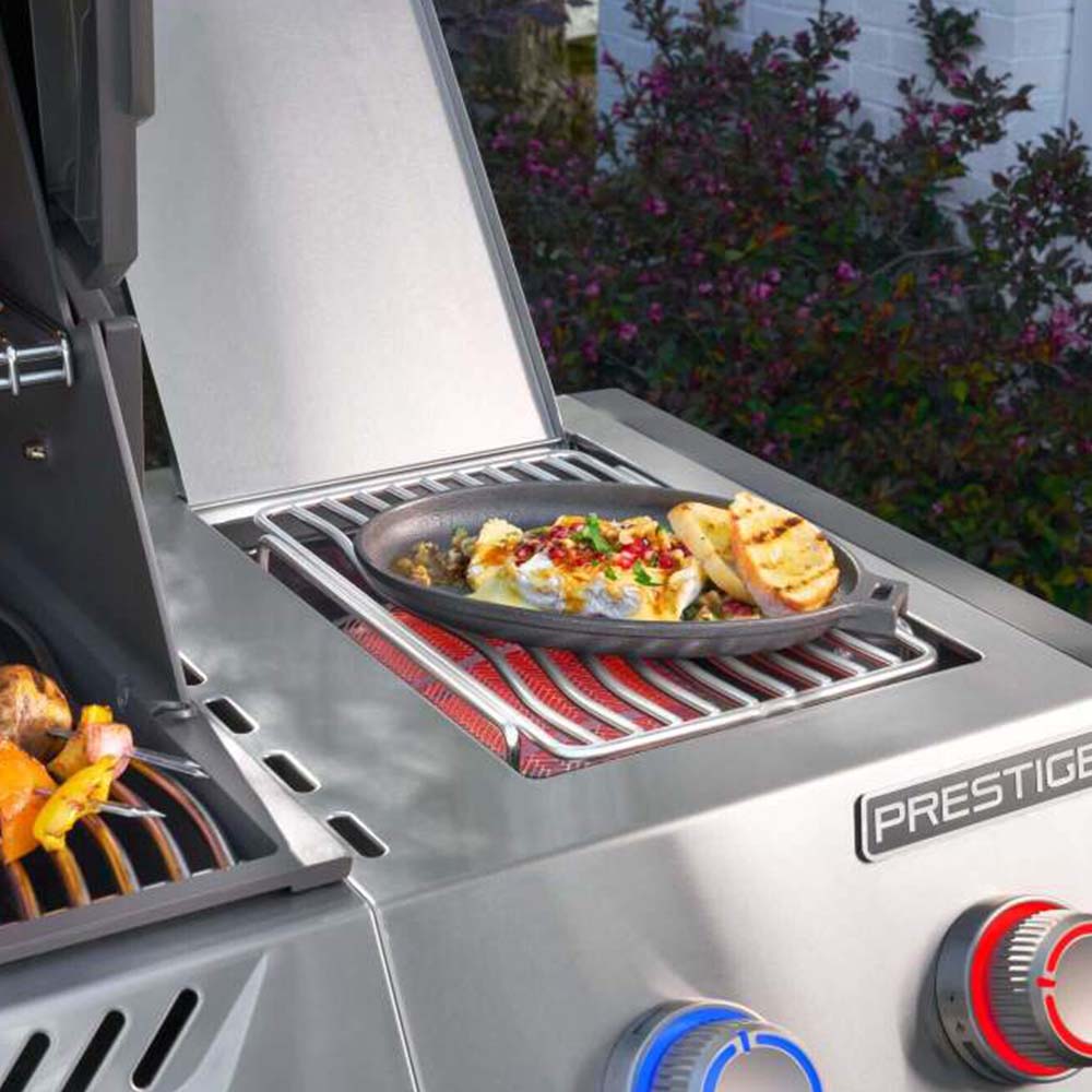 Gas grill side grate with food cooking and control knobs visible
