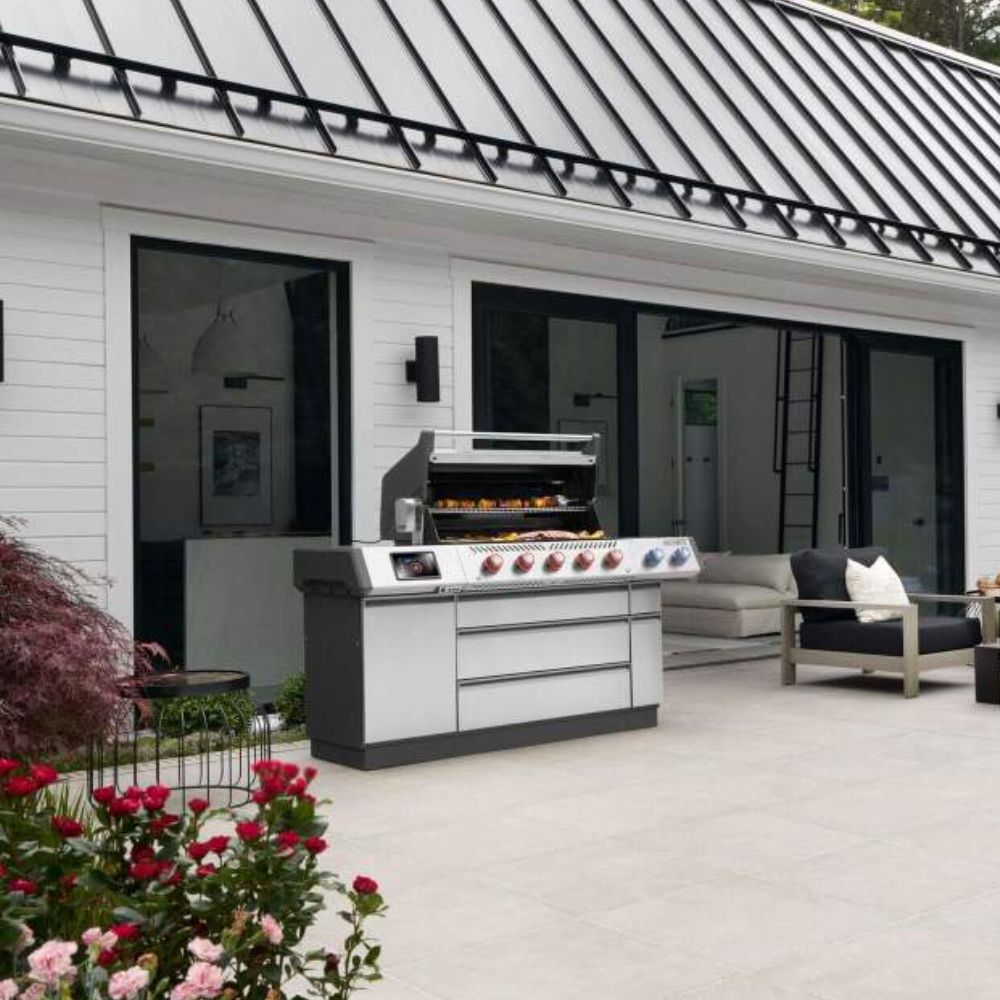 Stainless steel gas grill with open hood, side cabinet, and burner controls