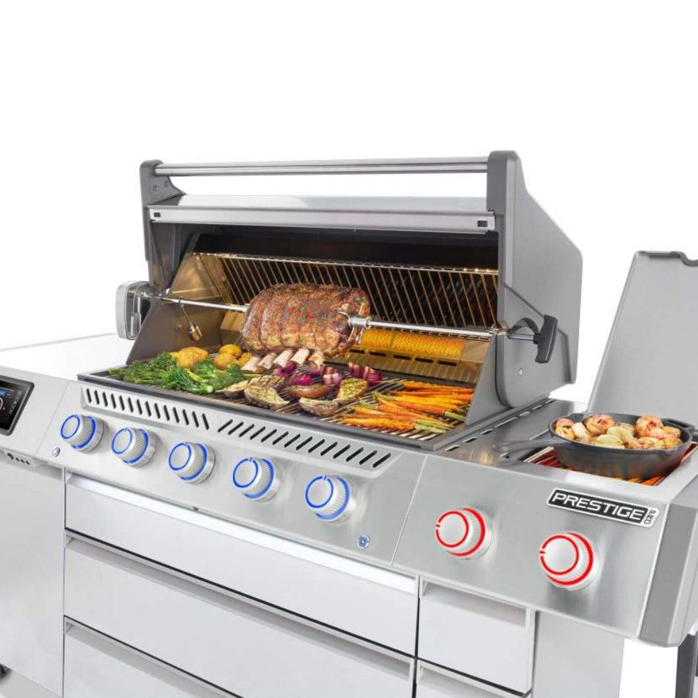 Gas grill with hood open, meats and vegetables on grates, front control knobs