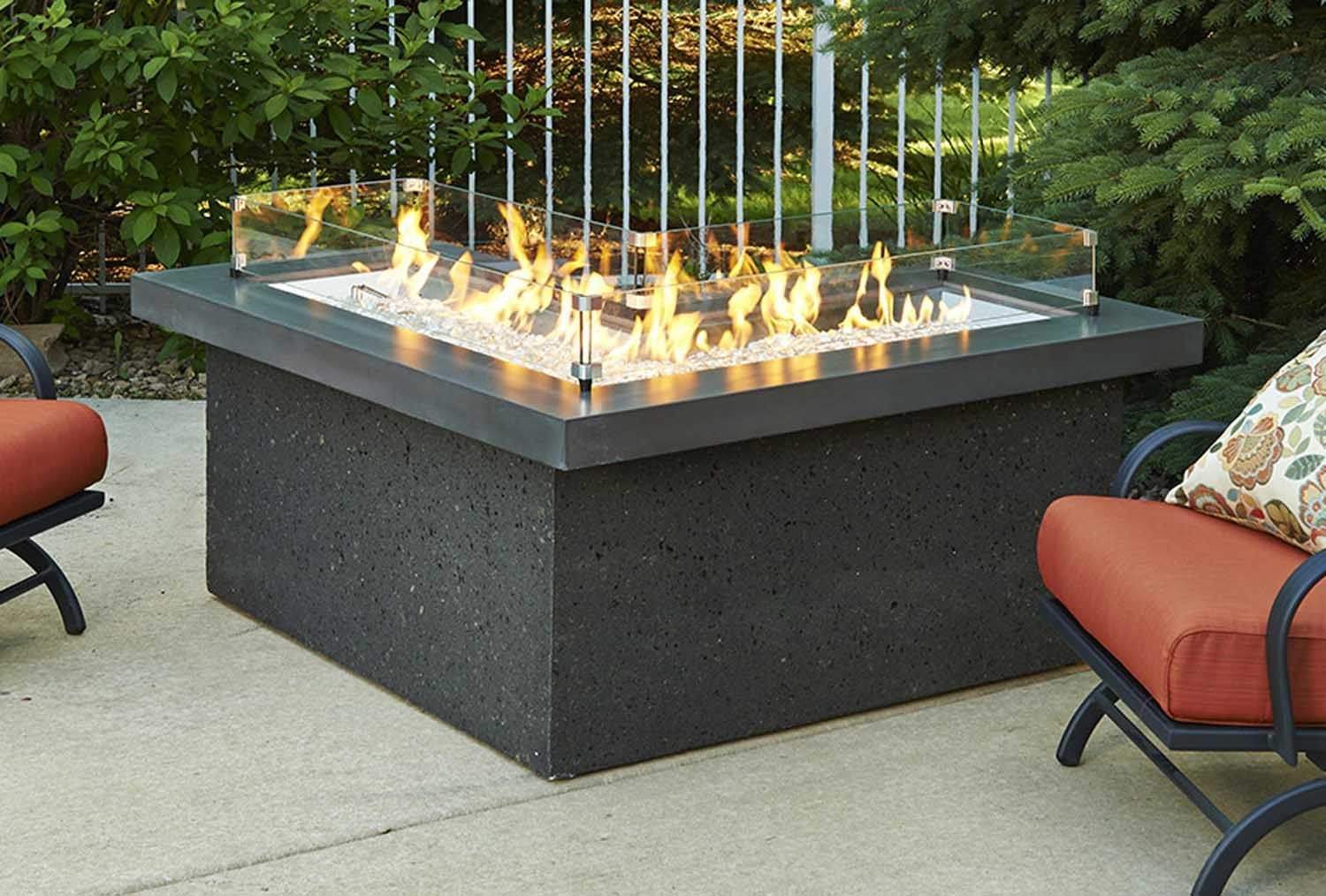 L-shaped glass wind guard on outdoor fire table, clear glass panels and flames