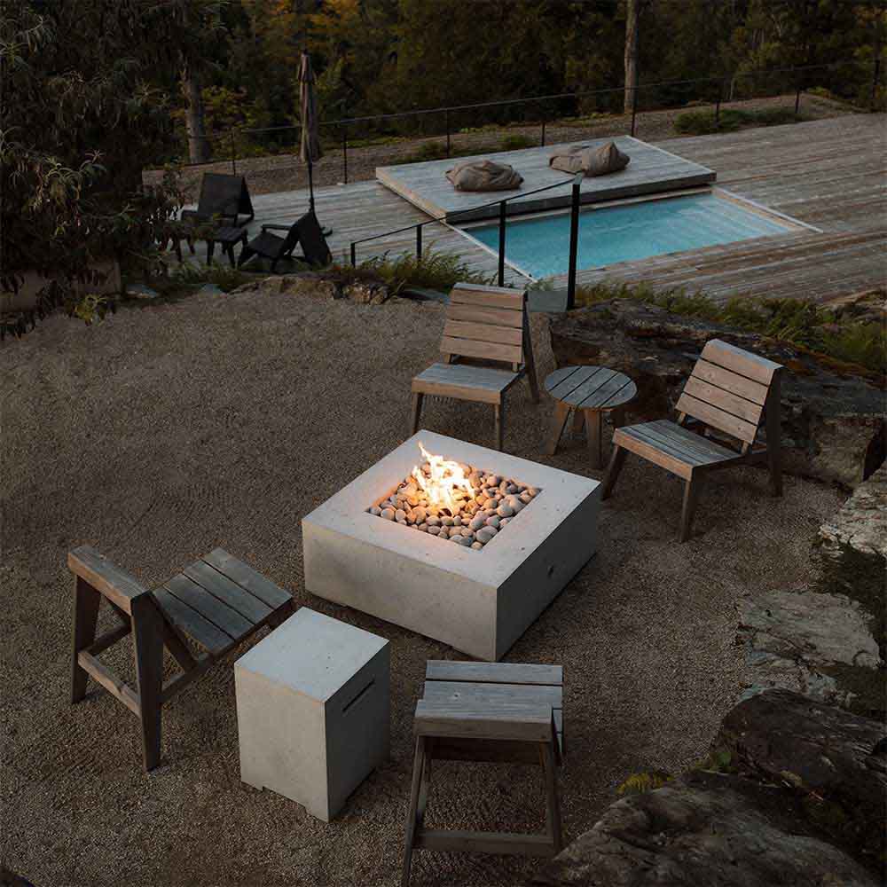 Concrete propane tank cover used as a fire pit base with stone burner area and flames.