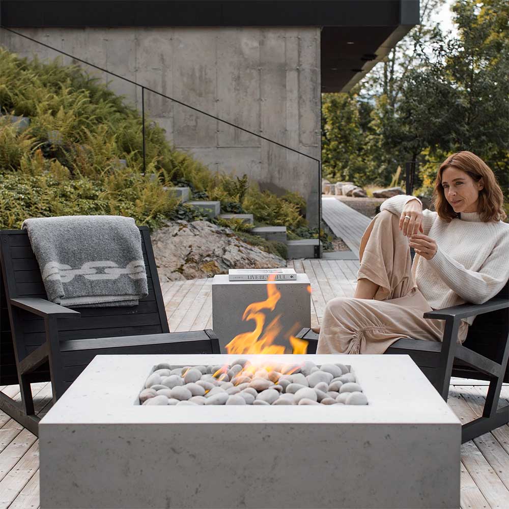Concrete propane tank cover/fire pit enclosure with open front and visible flames over stones.