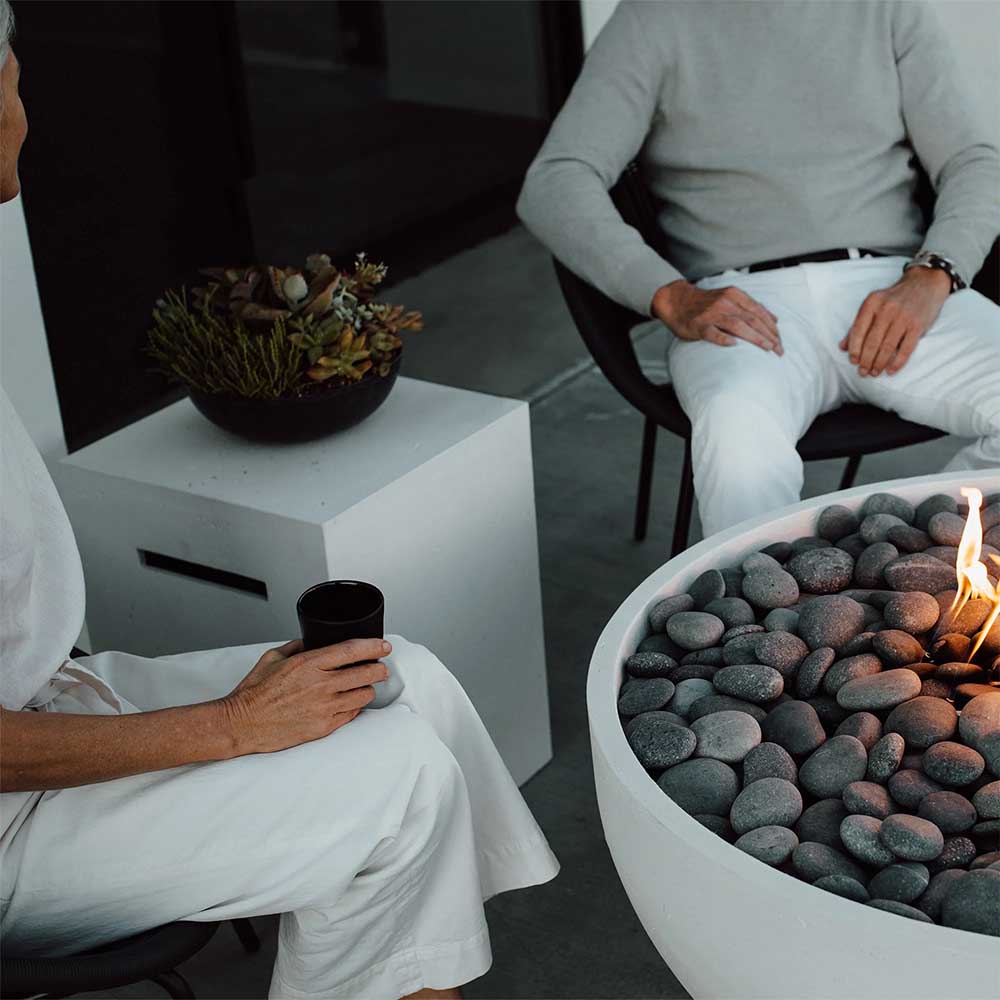 Concrete propane tank cover in a seating area, with flame visible near the stone burner.