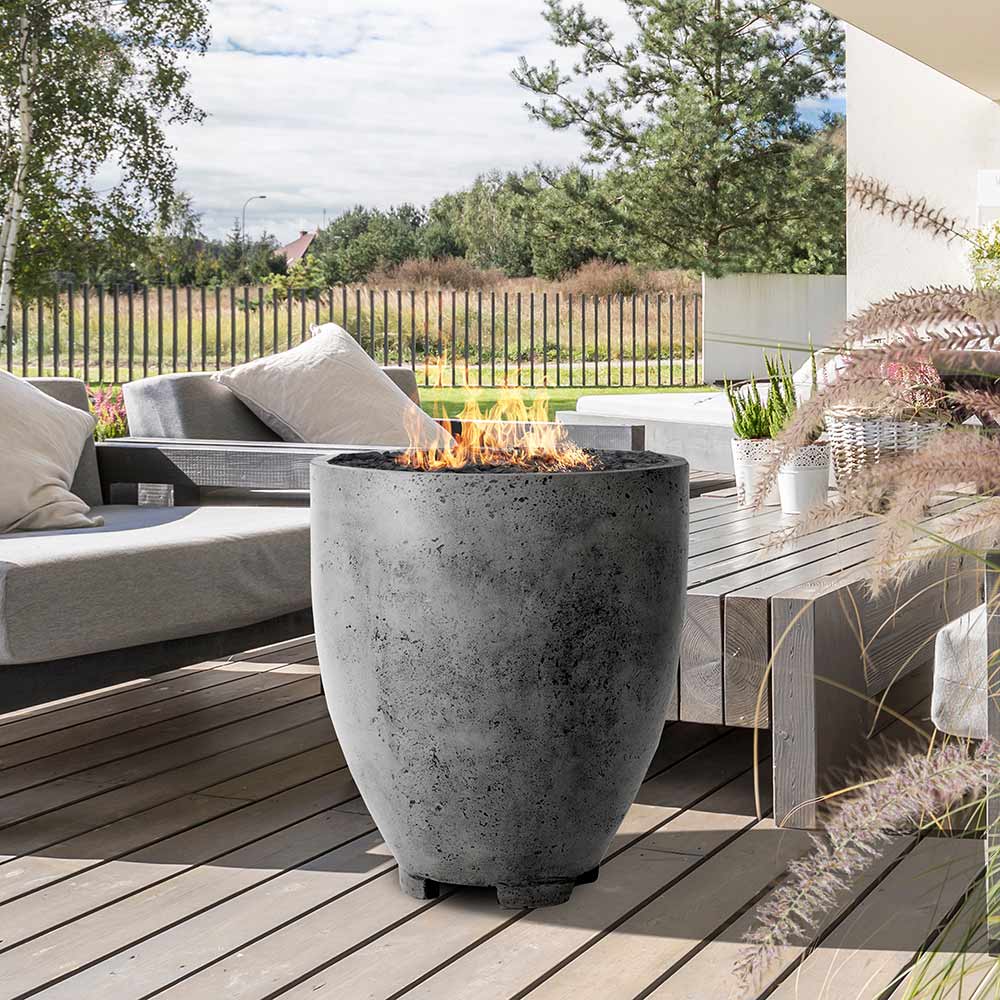 Concrete gas fire pit with round drum shape, dark gray finish, burning flame opening