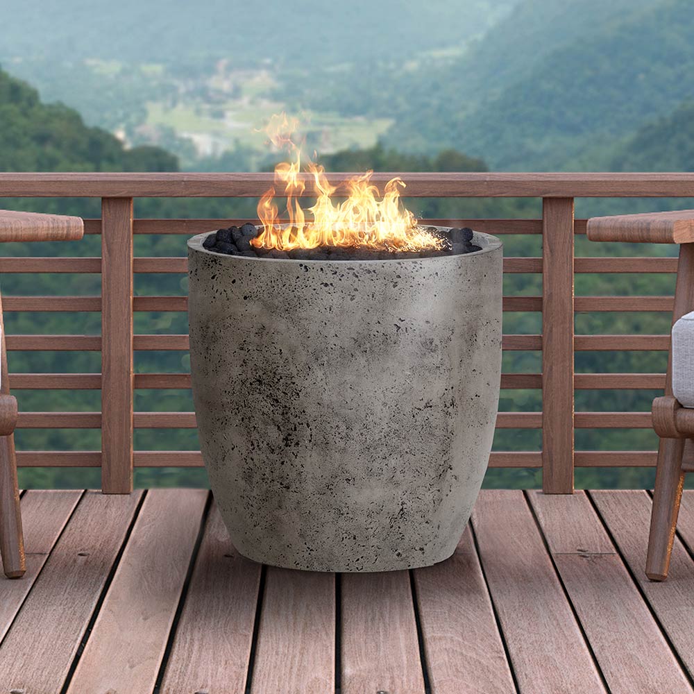 Concrete gas fire pit with open flame in dark gray speckled bowl on outdoor deck
