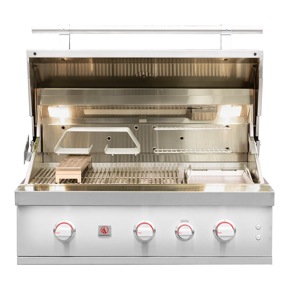 Built-in gas grill open lid showing burners, grates, and warming area inside.