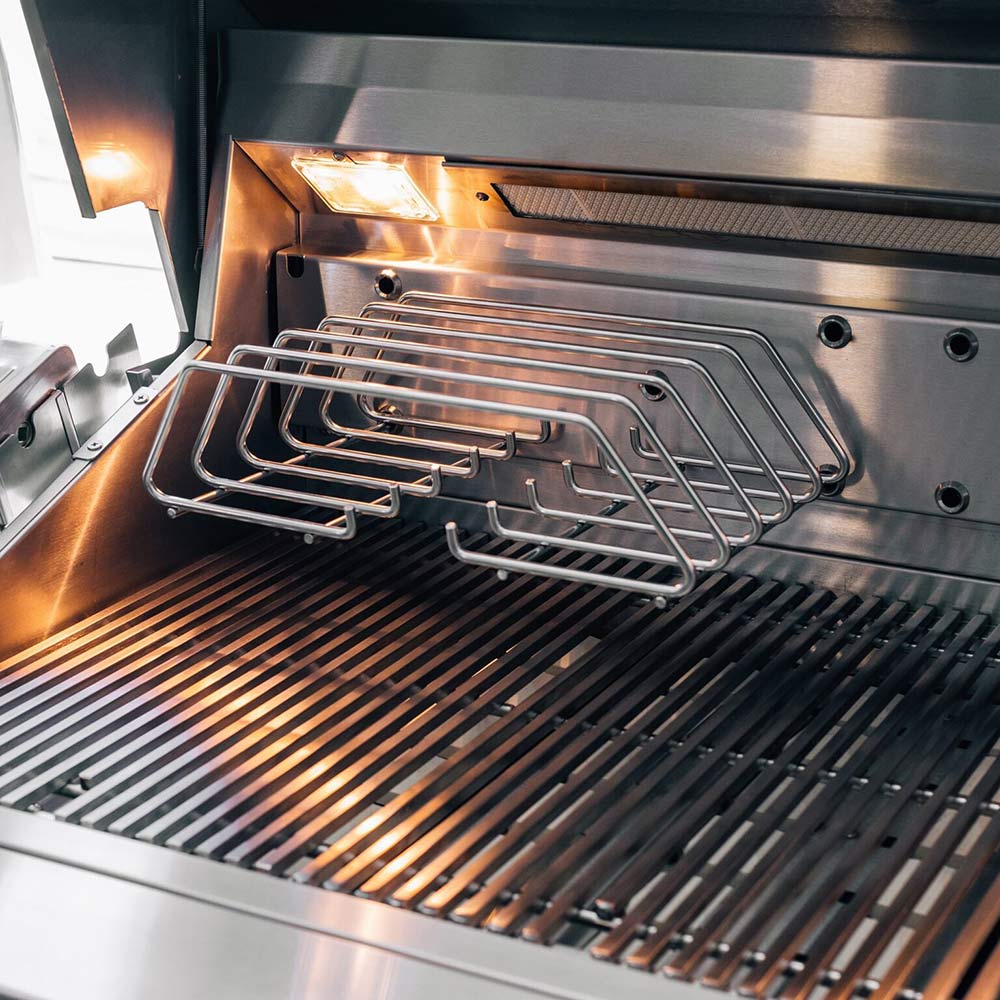 Built-in gas grill open lid showing stainless cooking grates over dark grill bars