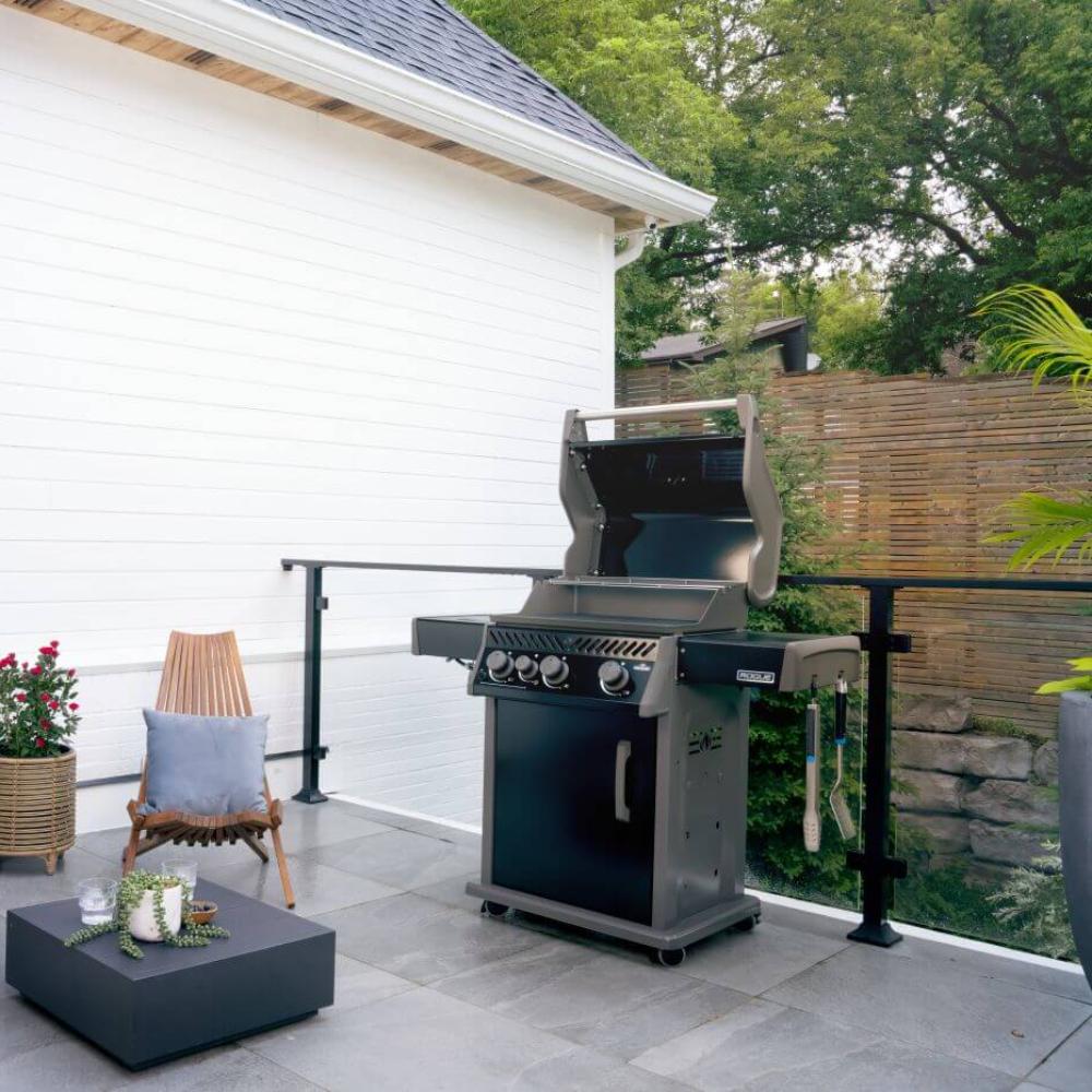 Black gas grill on outdoor patio with lid open and side shelf attached