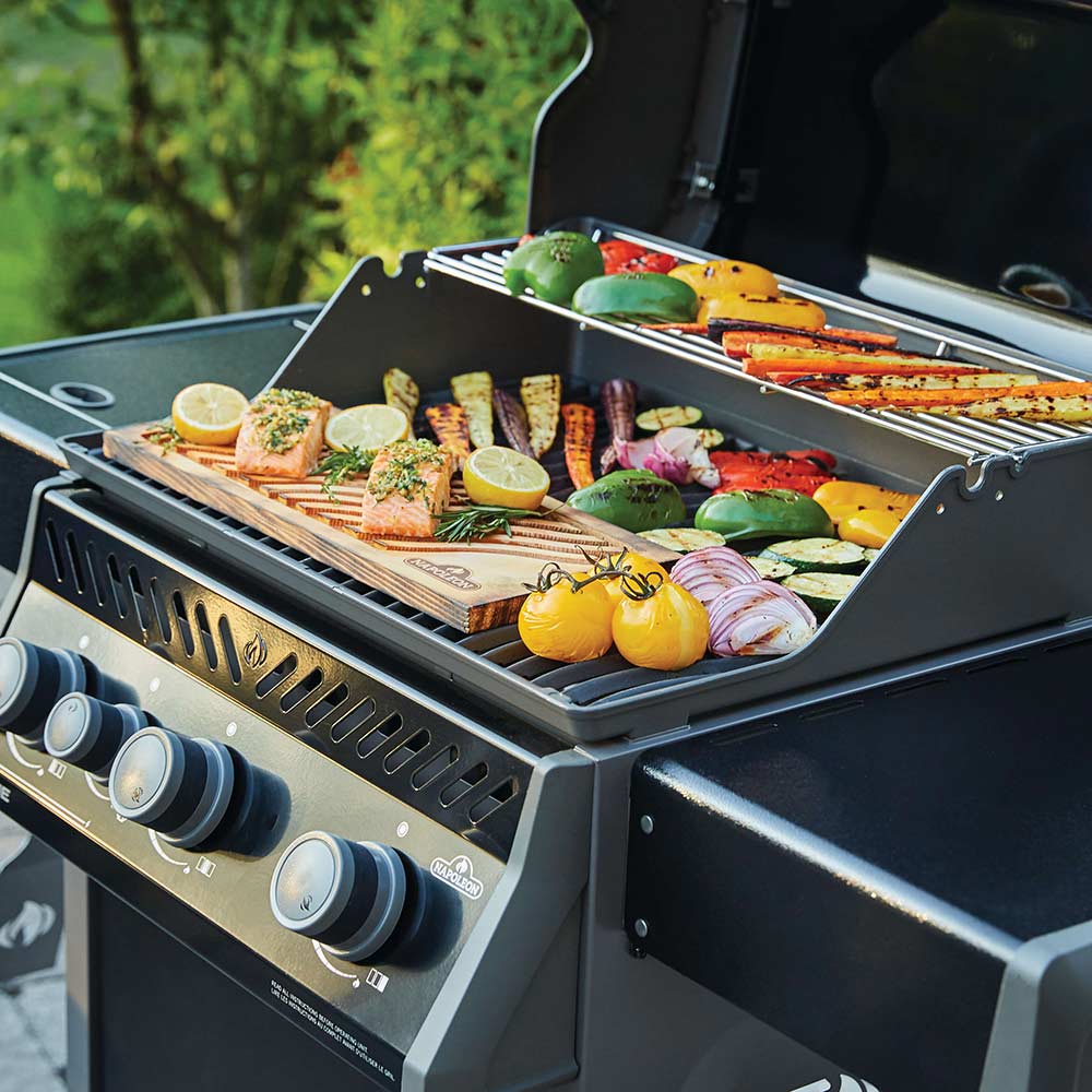 Gas grill with vegetables on sheet tray on the cooking surface