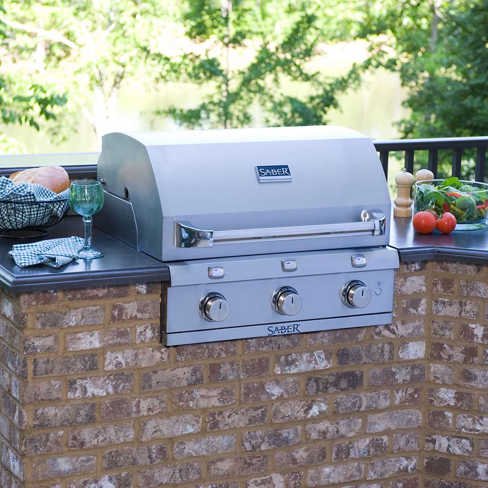 3-burner built-in gas grill on brick outdoor counter with stainless lid and knobs
