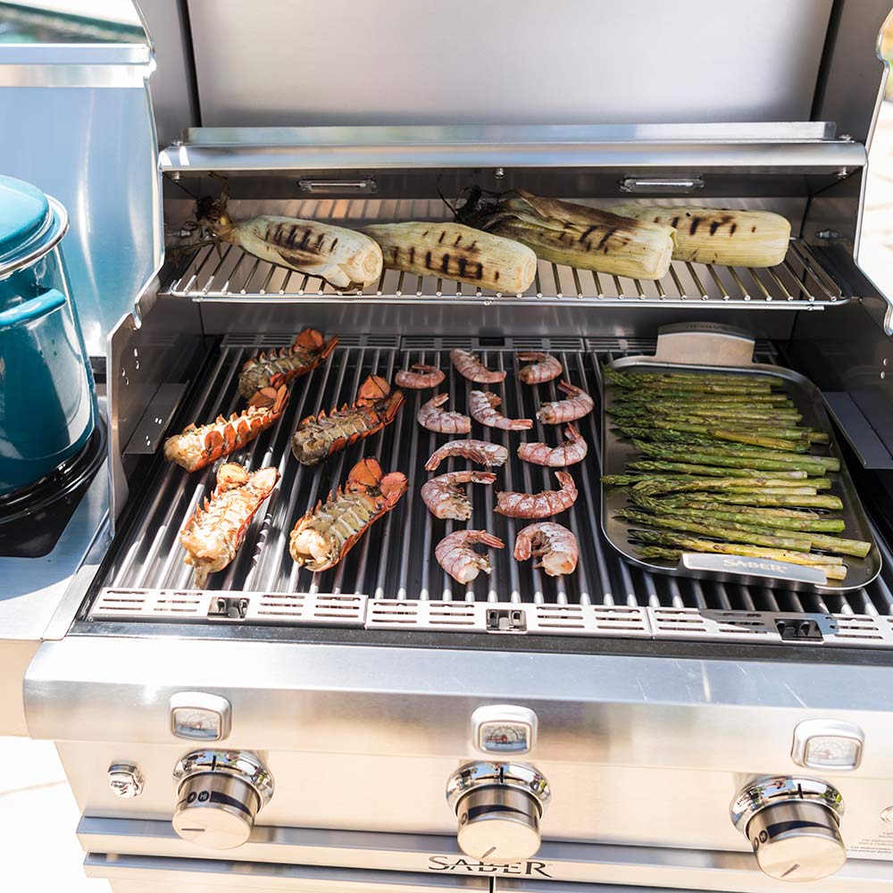 Infrared grill cooking surface with shrimp, sausage, and asparagus on grates