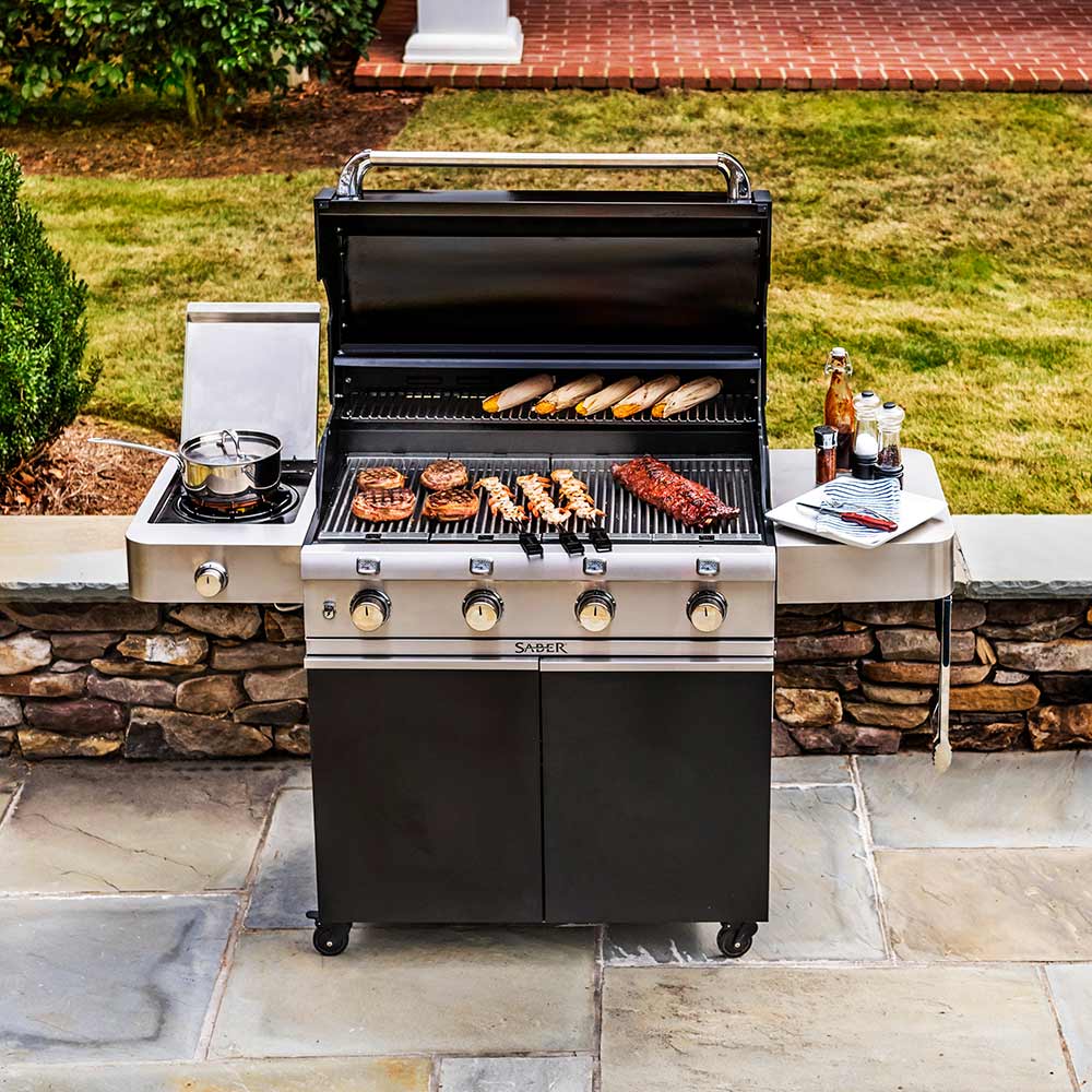 Black freestanding infrared grill with open lid, patties on grates and side burner