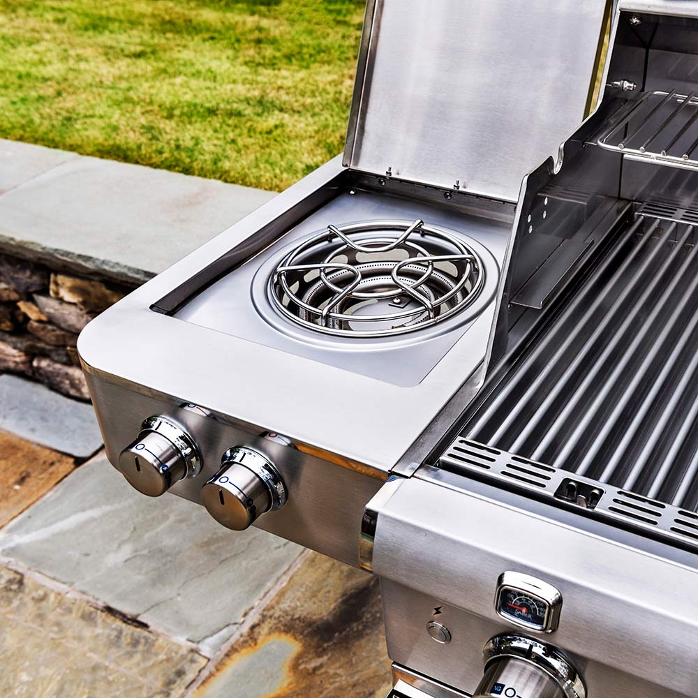 Stainless steel side burner with circular grate and control knobs on the grill