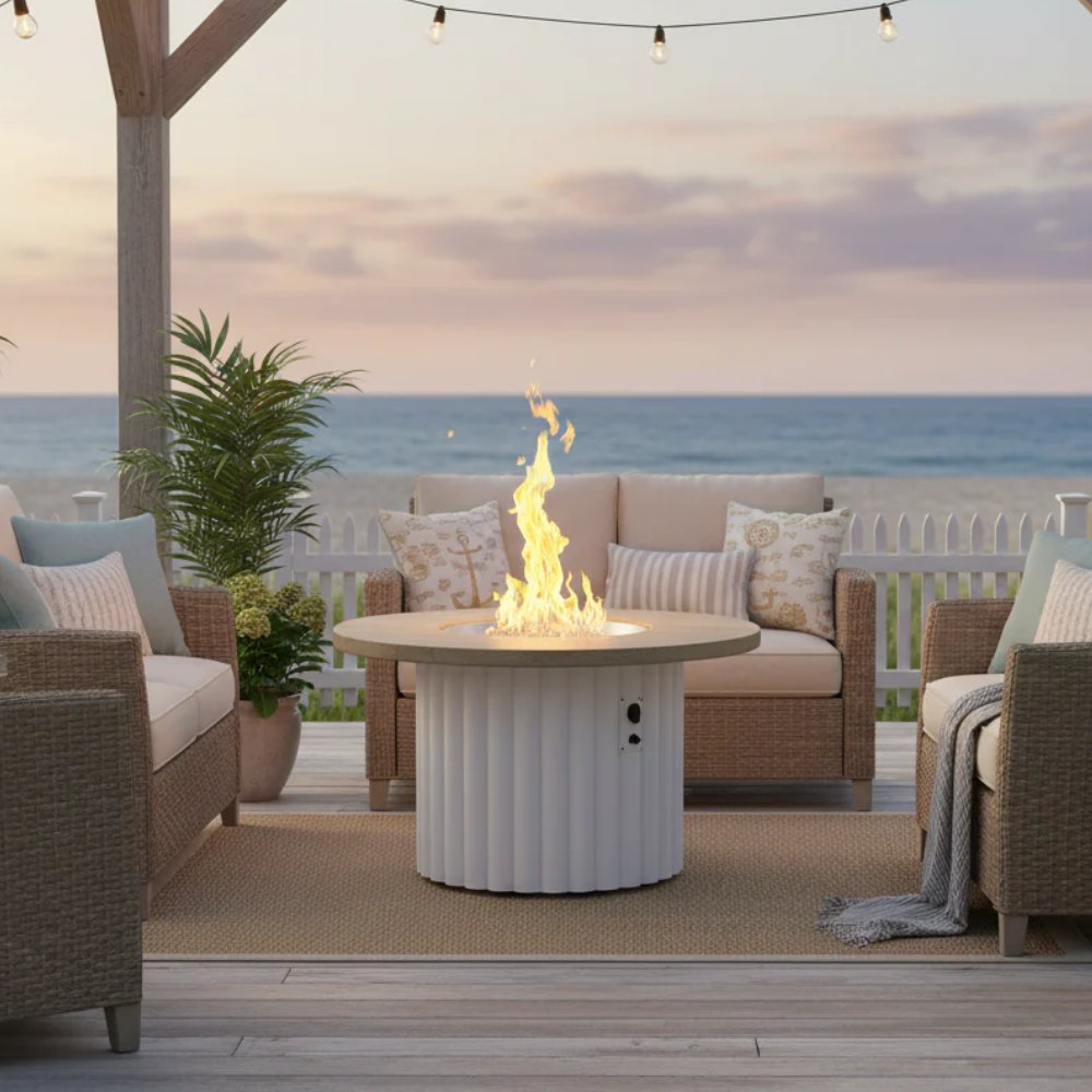 Round gas fire pit table with glowing flames, beige top, white ribbed base