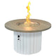 Round gas fire pit table with light wood top and white fluted base; flames in center bowl.