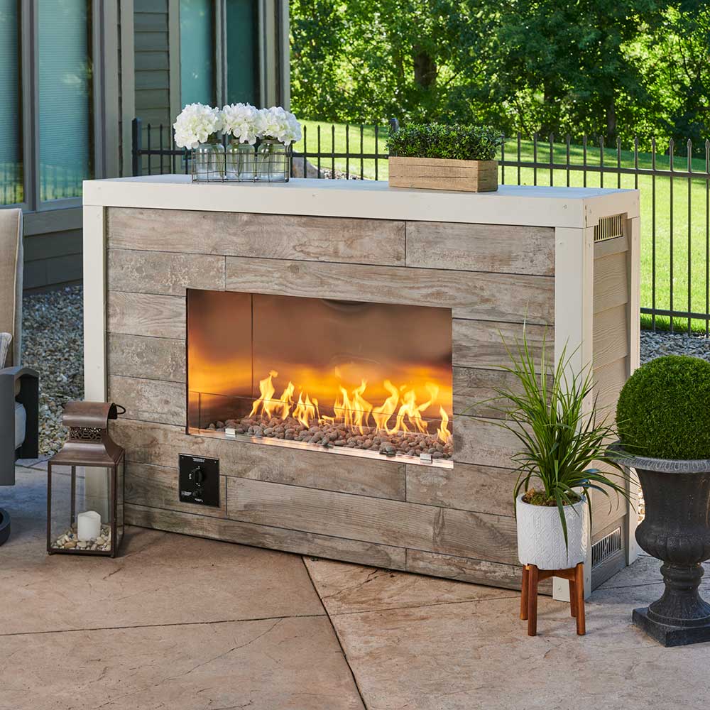 Outdoor linear fireplace insert with glass front and burning logs