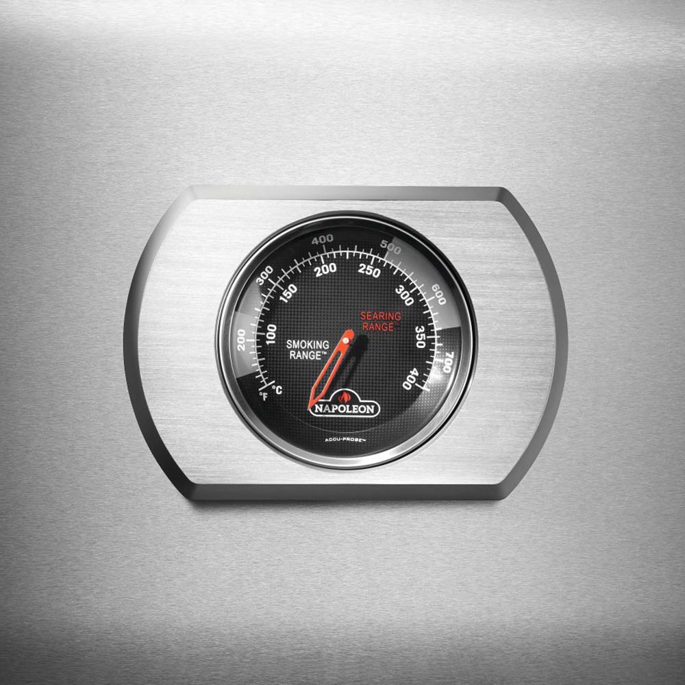 Stainless steel temperature gauge dial on gas grill lid with Napoleon branding