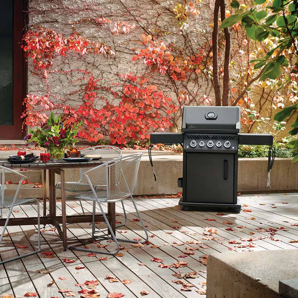 Black gas grill on cart outdoors with side table and control panel visible
