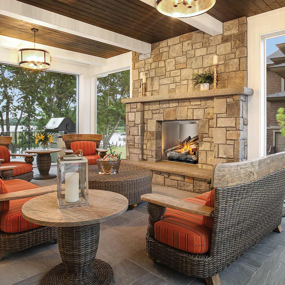 Outdoor gas fireplace with burning logs in a stone surround and open firebox