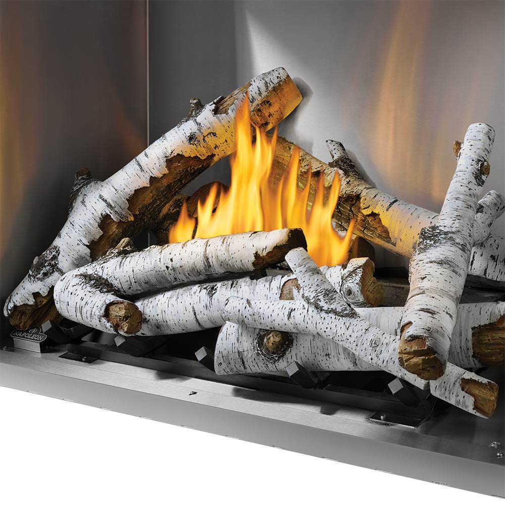 Outdoor gas fireplace interior with yellow flames and white birch log set