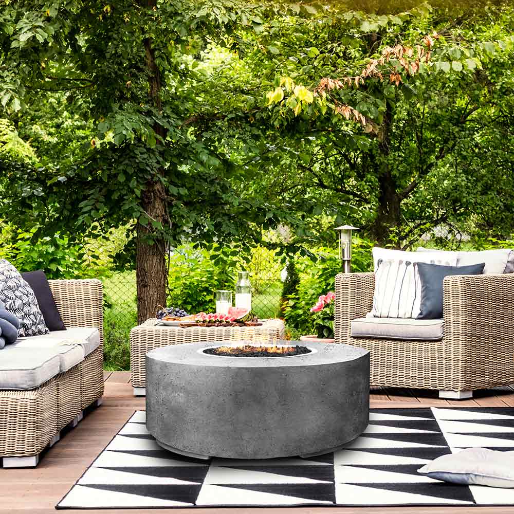 Round concrete gas fire pit with recessed burner opening in gray finish on patio