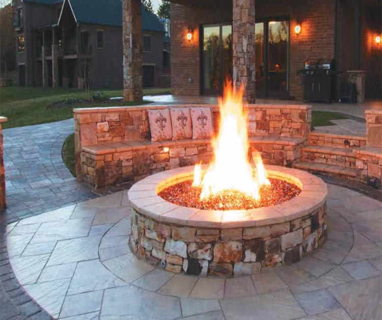 Gas fire pit burning spur with visible flame rising from a central burner ring