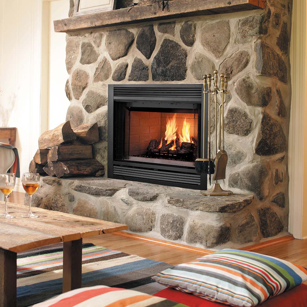 Wood-burning fireplace insert with open front, burning logs, and fireplace tools