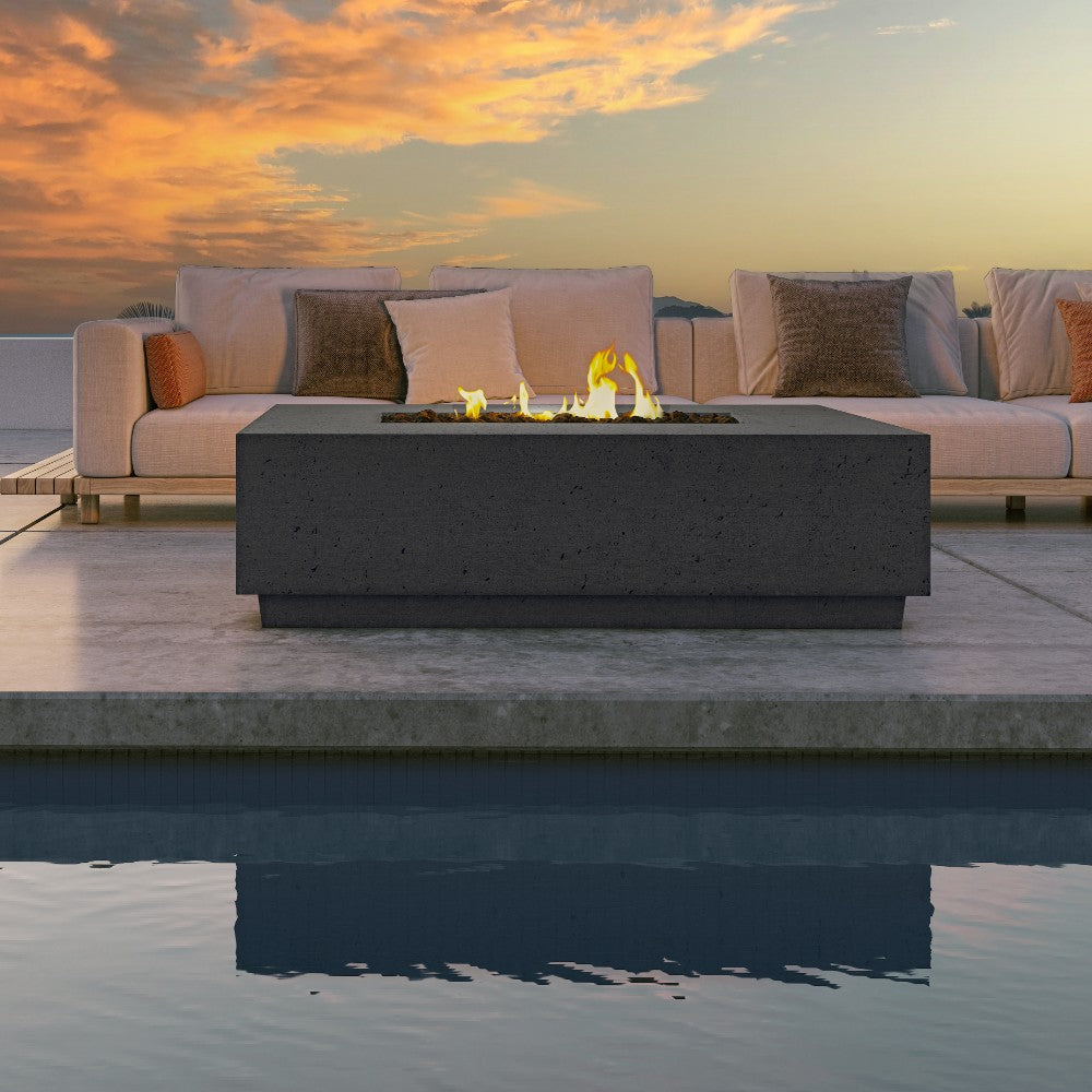 Outdoor gas fire table with lit flames in rectangular burner pan and concrete base