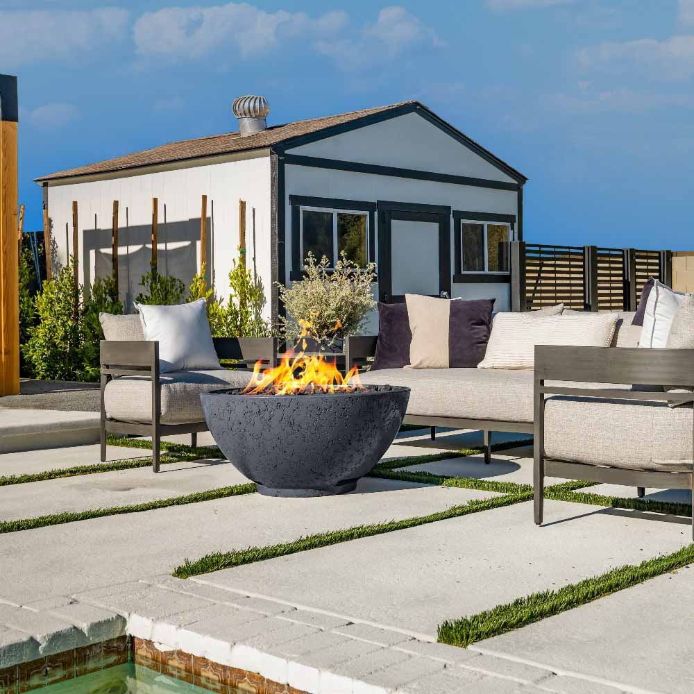 Gray gas fire bowl centered on patio, flames burning in open round basin