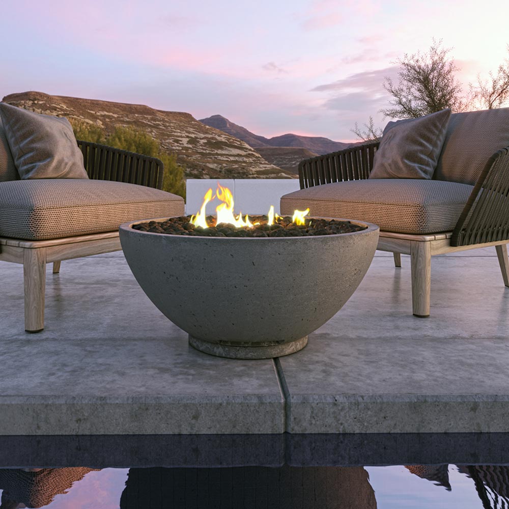 Outdoor gas fire bowl with flames, light gray stone finish on pedestal base