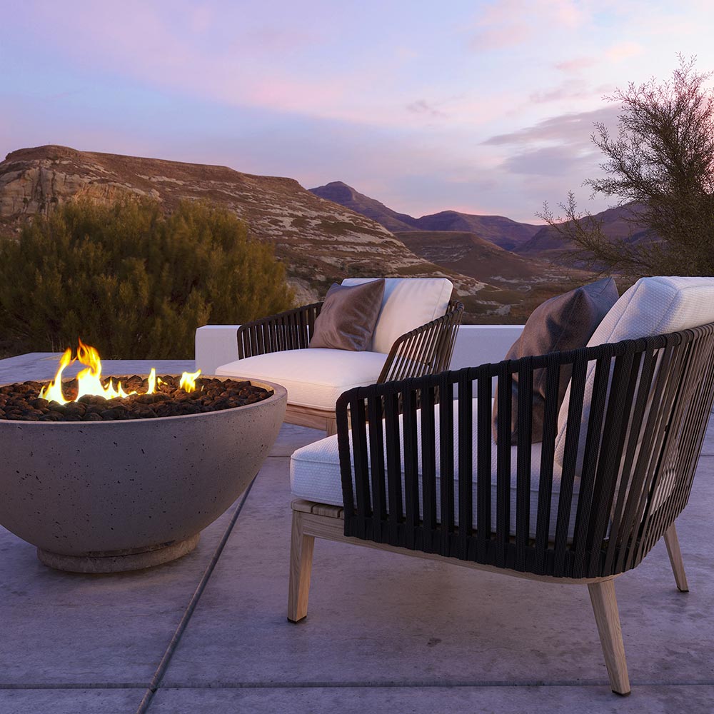 Outdoor gas fire bowl with flames, light gray stone finish on concrete patio