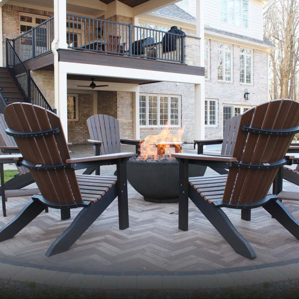 Gas fire bowl heater in dark finish with flames on outdoor patio near seating