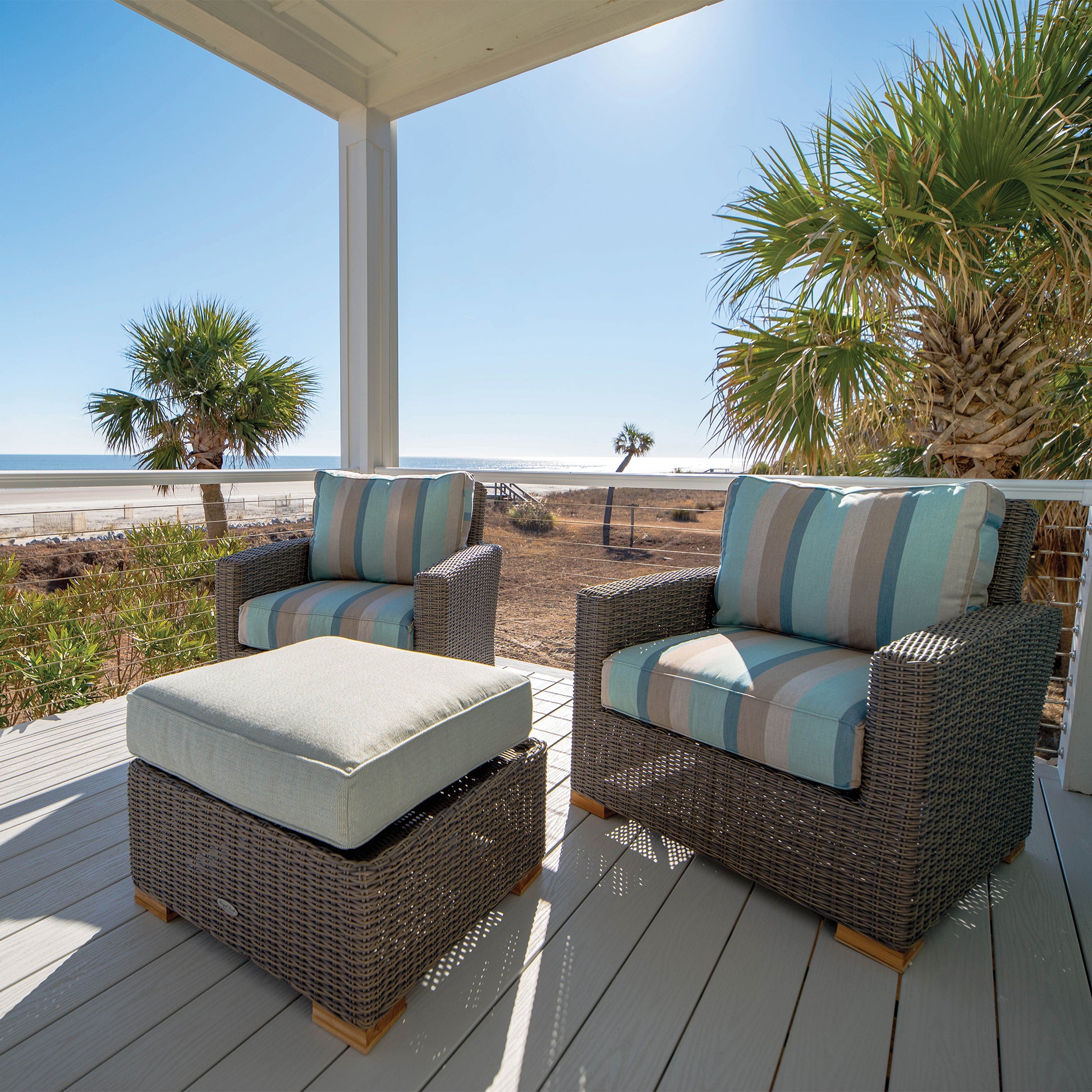 Outdoor seating set with striped blue cushions, woven loveseat, and matching ottoman