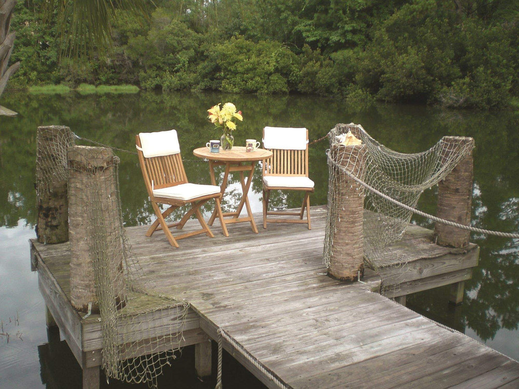Set of teak folding side chairs with slatted backs and seats arranged outdoors