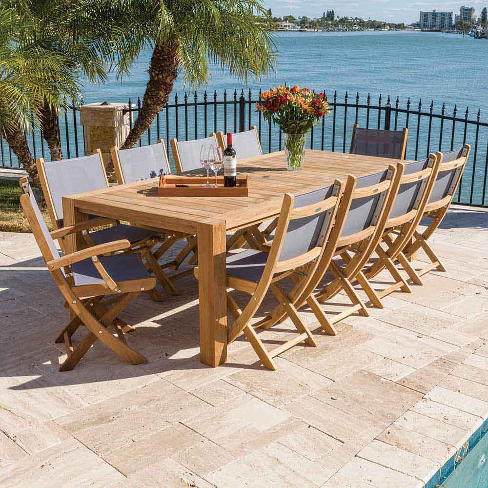 Folding teak arm chair with light-colored sling seat and backrest, on outdoor patio.