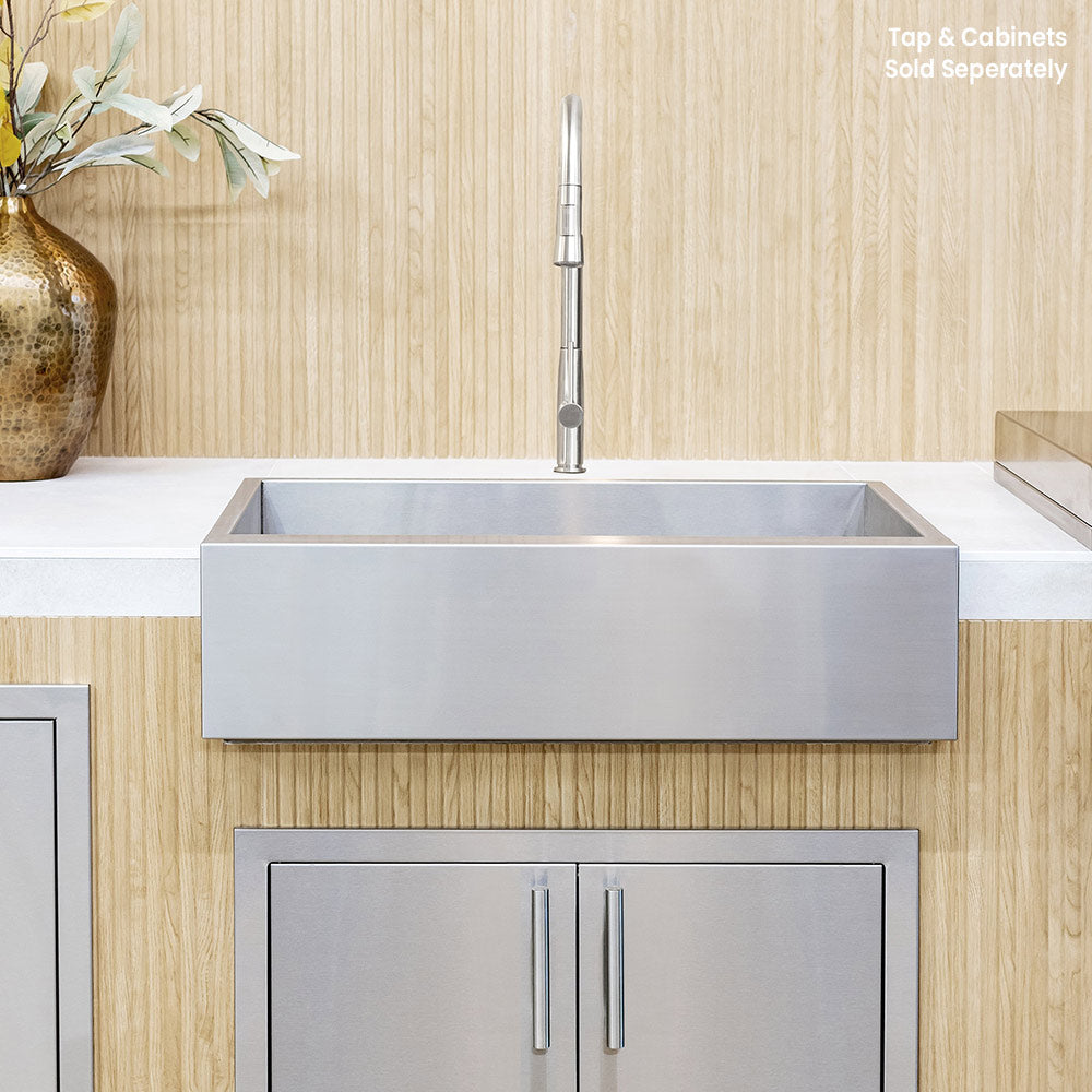 Stainless steel farmhouse sink with wall-mounted faucet above countertop