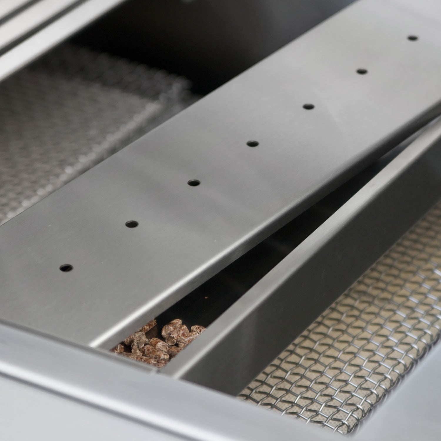 Stainless steel wood chip smoker box with drilled lid and visible wood chips