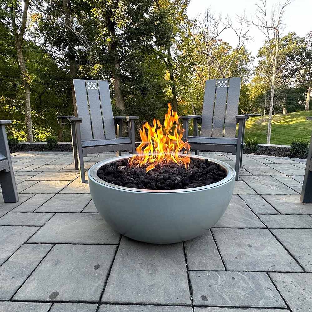 Round gas fire bowl with active flames and dark fire pit media