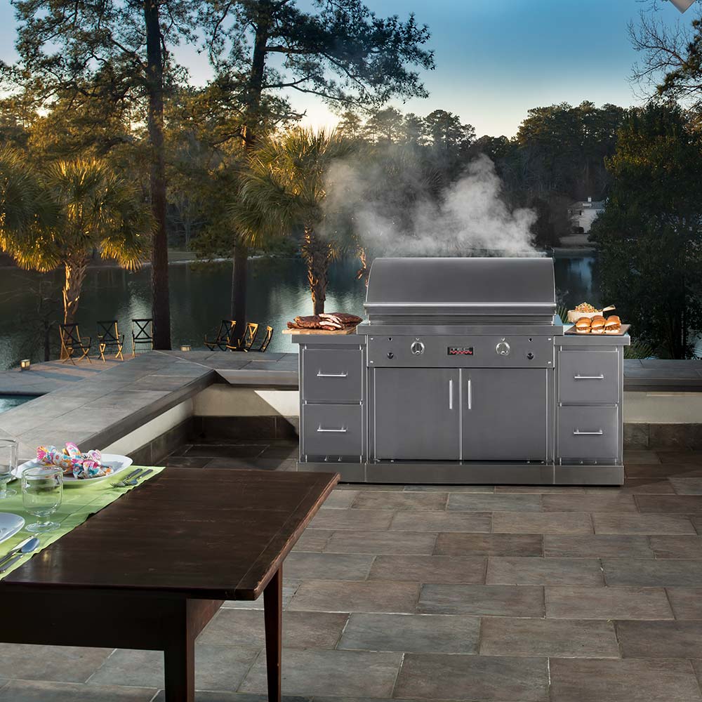 Stainless steel infrared gas grill outdoors with open hood and light smoke