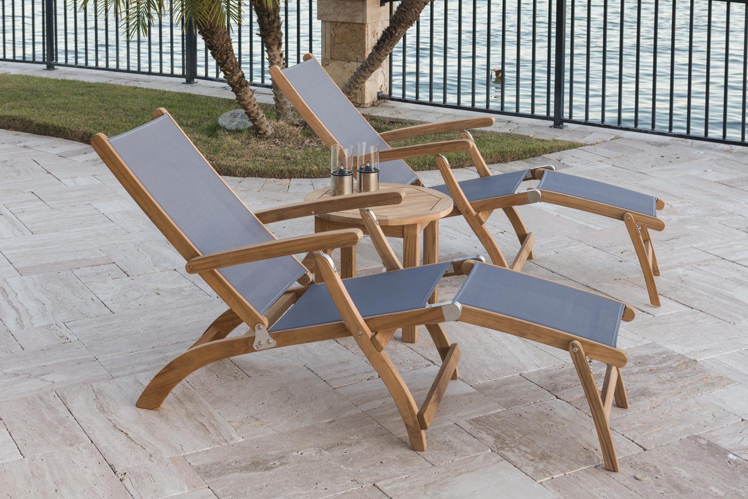 Teak steamer sling chair with light blue cushioned sling back and footrest.